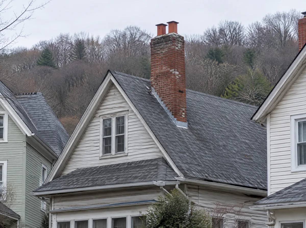 Older brick chimney with two flues on a steep roof of a village house
